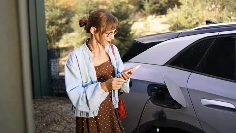Woman Using Phone While Charging Electric Car Stock Footage 282966103