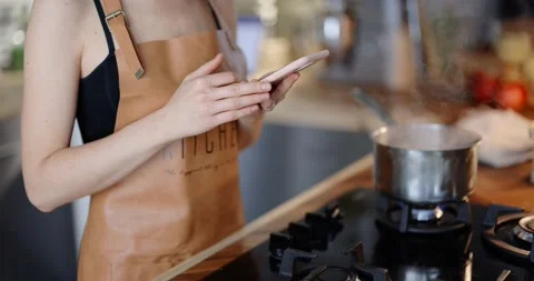 Woman using phone while cooking Stock Footage 146753054