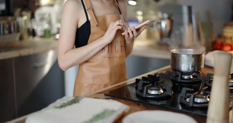 Woman using phone while cooking 스톡 동영상 146753265