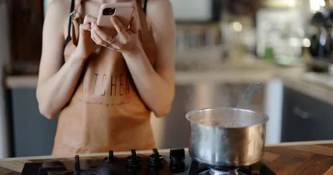 Woman using phone while cooking Stock Footage 146753429