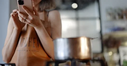 Woman using phone while cooking Stock Footage 146753643