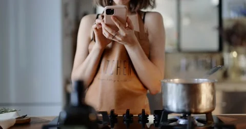 Woman using phone while cooking Stock Footage 146753826
