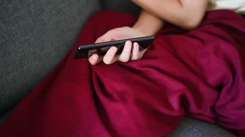 Woman using phone while lying down on sofa Stock Footage 146770332