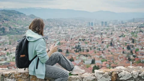 A woman using a phone while sitting on the hill with a beautiful top view  Stock Footage 241211461