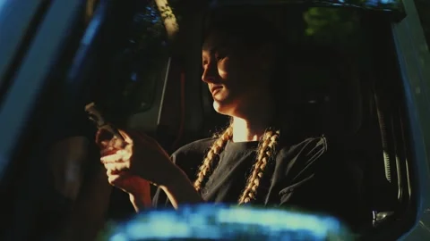 Woman using a phone while sitting in a forest at sunset, bathed... Video stock 341613065