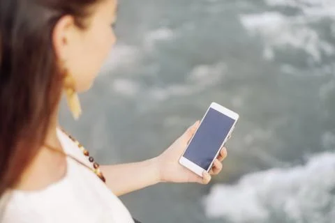 Woman using phone while walking near the river. Stock Photos