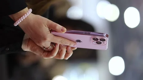 Woman using pink 14 pro iphone, close up shot, blurred background. Stock Footage 277607895
