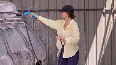 Woman using a pressure washer applying foam at a self service car wash station 库存影片 344810646