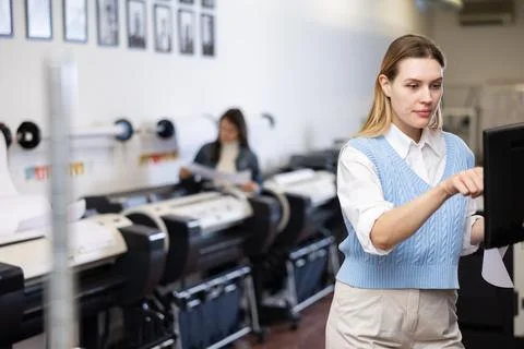 Woman using printer while working in print shop 写真素材