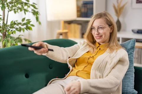 Woman using remote control for TV Stock Photos