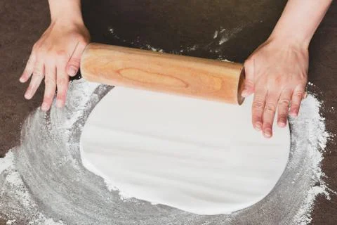 Woman using rolling pin preparing royal icing for cake decorating, hands deta Foto stock