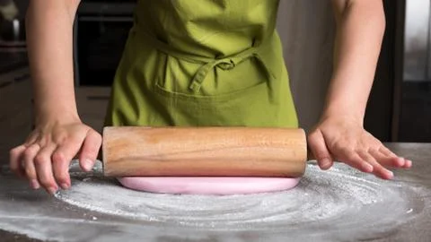 Woman using rolling pin preparing pink fondant for cake decorating, hands det Stock Photos