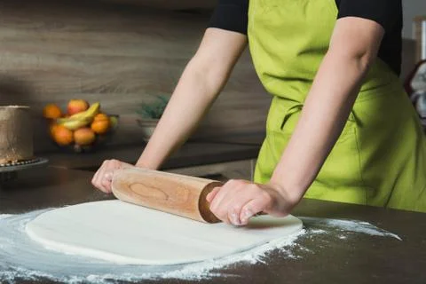 Woman using rolling pin preparing white fondant for cake decorating, hands de Foto stock