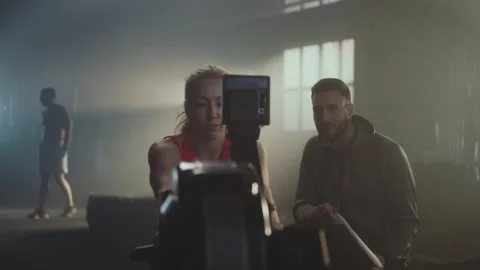 Woman using rowing machine with trainer Vídeos de archivo 236182521