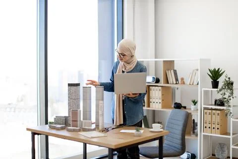 Woman using ruler while checking data on laptop at work Stock Photos