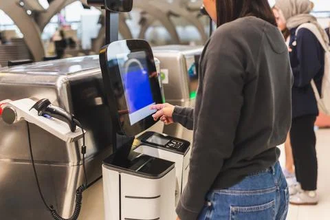 Woman using service machine for self check in at airport. Stock Photos