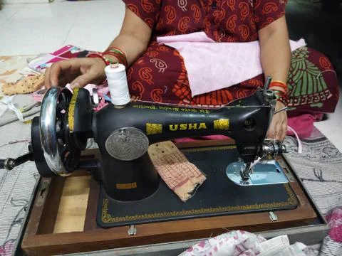 A woman is using the sewing machine to do tailoring on clothes. Stock Photos