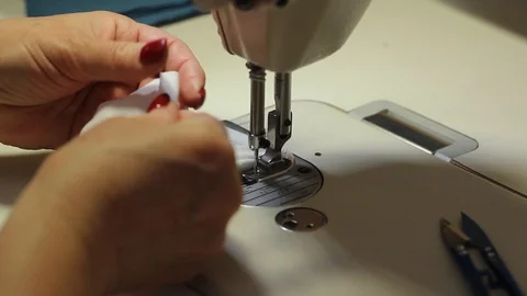 Woman using a sewing machine makes protective masks from cotton fabric. Stock Footage 127840355