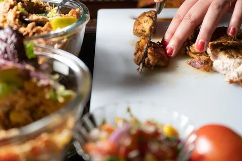 Woman using a sharp knife to cut meat, chiken, mutton, beef on a white choppi 스톡 사진