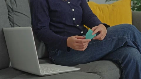 Woman using small brush to clean green menstrual cup while working on laptop at Stock Footage 340576452
