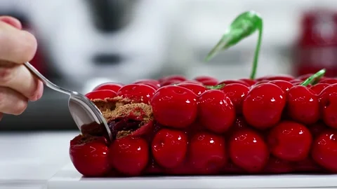 Woman using small spoon to cut pieces from modern 3d cake, close shot of plate Stock Footage 148556797