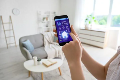 Woman using smart home application on smartphone for remote control of house  库存照片