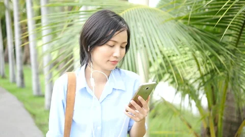 Woman using smart phone and walking in the park 库存影片 68385129