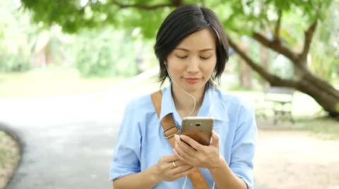 Woman using smart phone and walking in the park Stock Footage 68546309