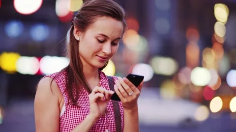 Woman using smart phone at night in city. 4K. Busy Street lights background. Stock Footage 67848418