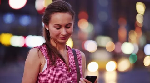 Woman using smart phone at night in city. 4K. Busy Street lights background. Stock Footage