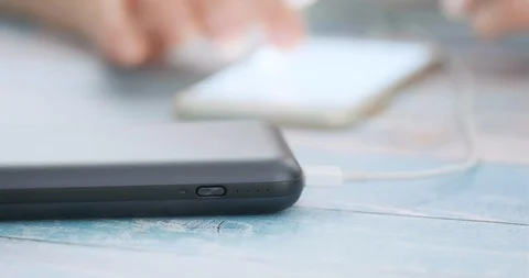 Woman using smart phone while charging on the power bank. 動画素材 102724222