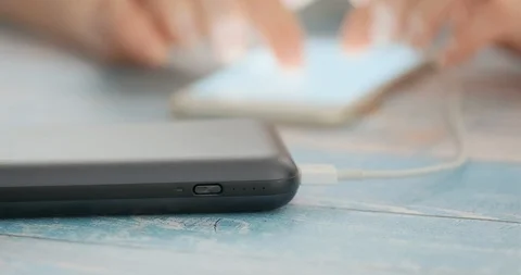 Woman using smart phone while charging on the power bank. 動画素材 102727472