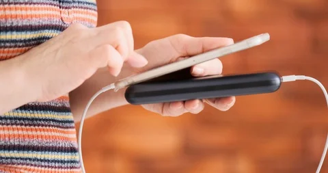 Woman using smart phone while charging on the power bank. 動画素材 103251432