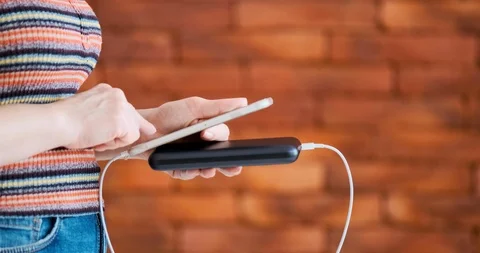 Woman using smart phone while charging on the power bank. 動画素材 103251455