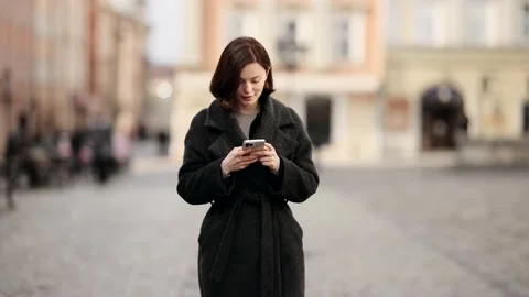 Woman using smart phone while standing outdoors on a city street. Attractive Stock Footage 166683294