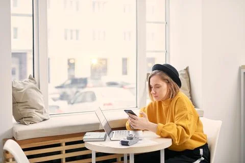 Woman using smart phone while working on laptop at cafe Stock Photos