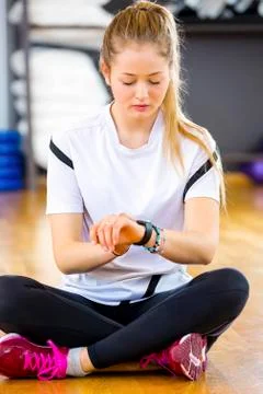 Woman Using Smart Watch While Sitting In Gym Stock Photos