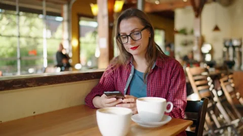 Woman is using smartphone and drinking coffee in the cafe Stock Footage 266862953