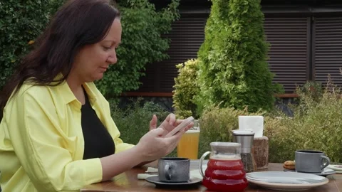 Woman using smartphone and drinking tea at outdoor cafe Video stock 312378252