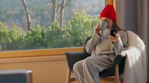 A woman using smartphone and drinking coffee in a quiet cabin. Video stock 343446957