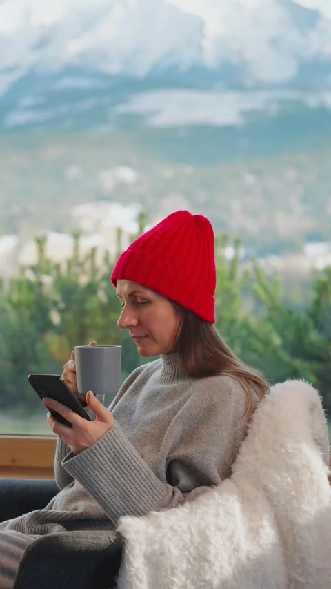 A woman using smartphone and drinking coffee in a quiet cabin. Video stock 343448353