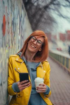 Woman using smartphone and drinking coffee takeaway Stock Photos