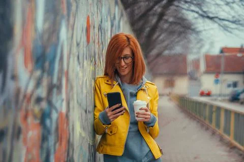 Woman using smartphone and drinking coffee takeaway Stock Photos