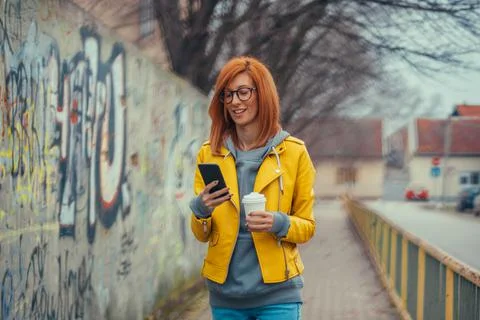 Woman using a smartphone and drinking coffee takeaway Stock Photos