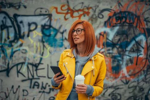 Woman using smartphone and drinking coffee takeaway Stock Photos