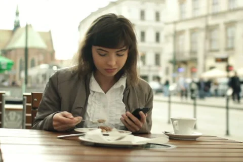Woman using smartphone and eating in the city, steadicam shot NTSC Stock Footage 10890341