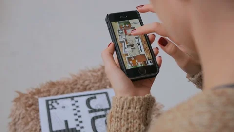 Woman using smartphone with augmented reality app, checking virtual house plan Stock Footage 83645379