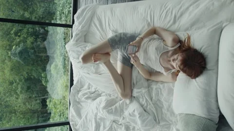 Woman using smartphone in bed with forest view Stock Footage 305356298