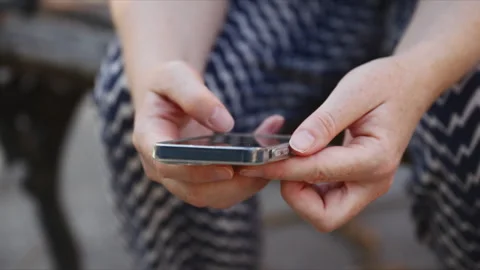 Woman using a smartphone with both hands in a close-up lifestyle scene. Mob.. Stock Footage 345499154