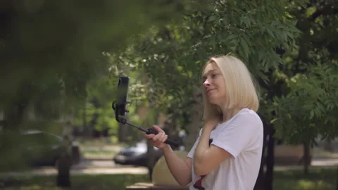 A woman using a smartphone is broadcasting live while walking in a Park Stock Footage 134336615